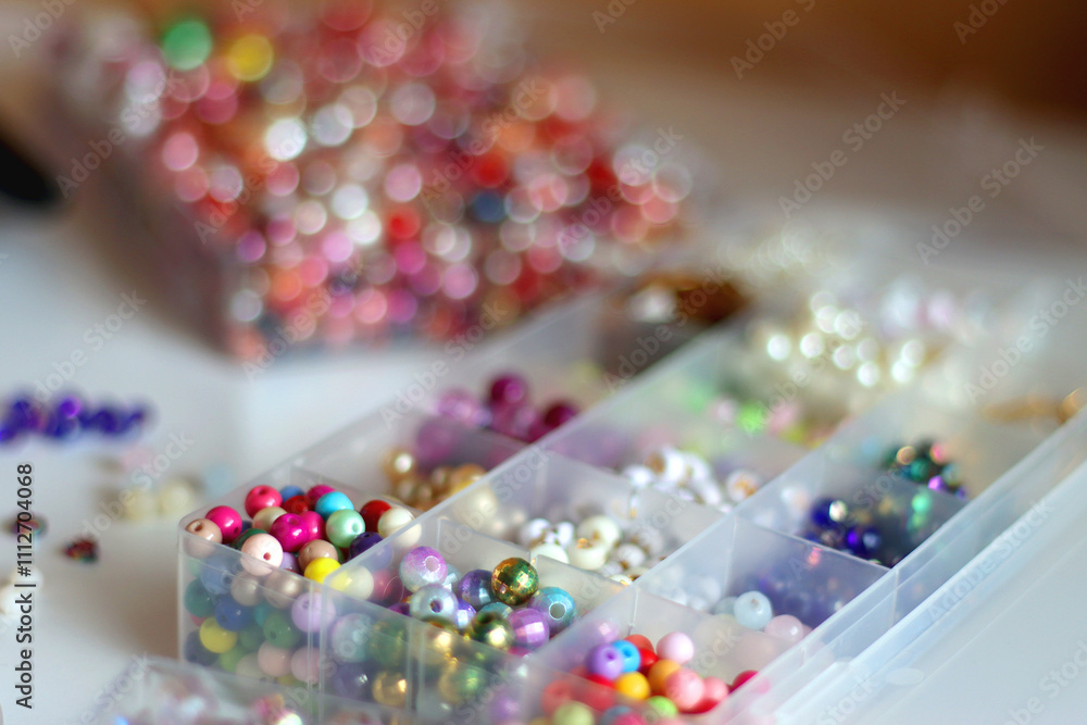 Hand figurine, colorful friendship bracelets, necklaces, various beads and DIY supplies on the table. Making jewelry at home. Selective focus.