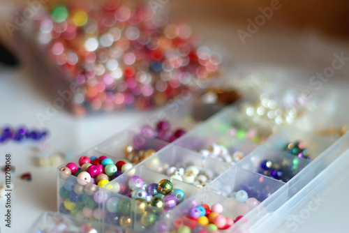 Hand figurine, colorful friendship bracelets, necklaces, various beads and DIY supplies on the table. Making jewelry at home. Selective focus.