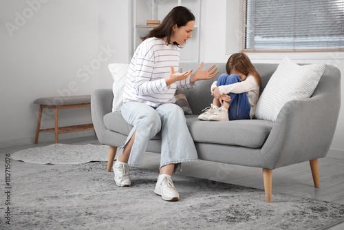 Scared little girl with her quarreling mother sitting on sofa at home. Domestic violence concept photo