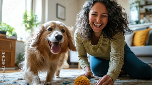 A woman enjoying a lively and engaging moment with her energetic dog, playing with a yellow ball in her living room, symbolizing joy and companionship.