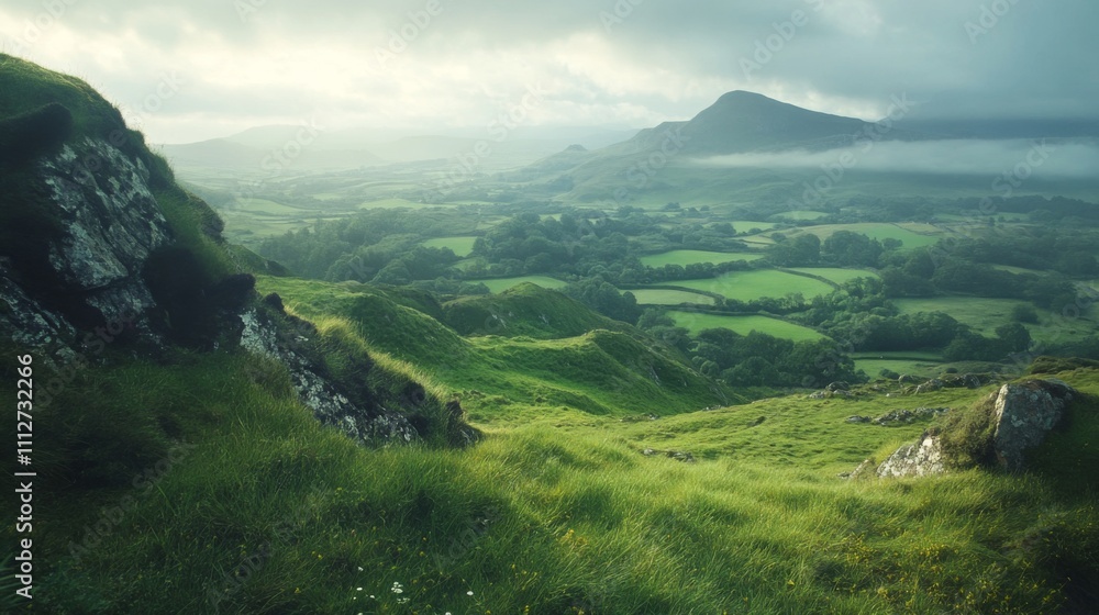 Obraz premium Rolling Green Hills with a Misty Mountain Peak in the Distance