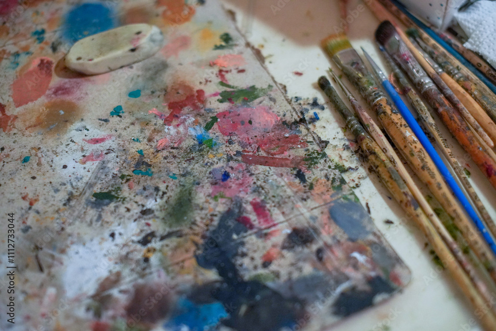 Fototapeta premium Paints and brushes are laid out on the table - this is the artist's workplace.