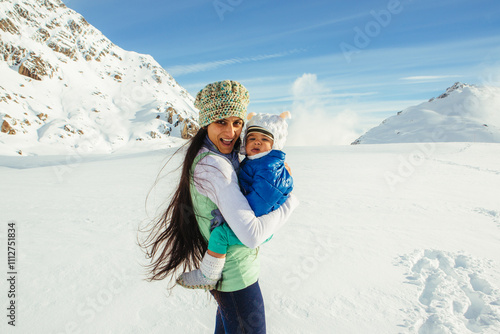 A beautiful Indian (Asian) mother and her one-year-old son pose in winter clothes in fresh snowfall on top of Fox Glacier in Weheka, South Island of New Zealand.