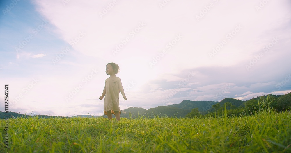 Fototapeta premium A young adorable child girl stands in a grassy field Sunlit Meadow gazing at the sky, Capturing a Sense of Wonder and Adventure in a Serene Natural