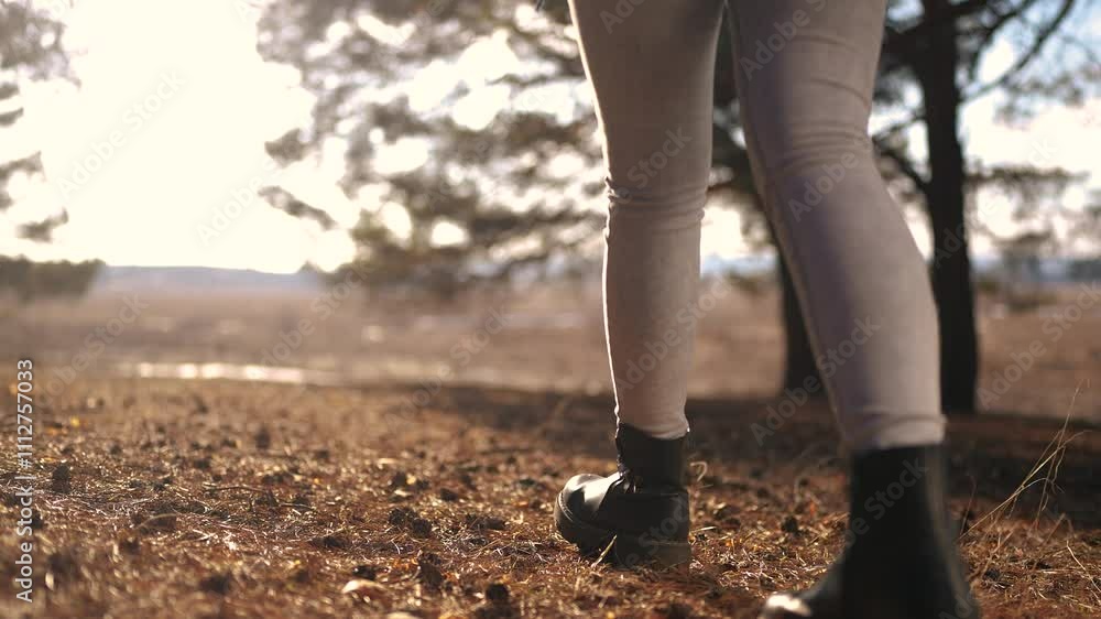 tourist girl walks through the forest. tourist recreation concept. female legs in black boots walk through a bright spring forest with glare of the sun lifestyle close-up. tourist tourist girl walks through the forest. tourist recreation concept. female legs in black boots walk through a bright spring forest with glare of the sun lifestyle close-up. tourist