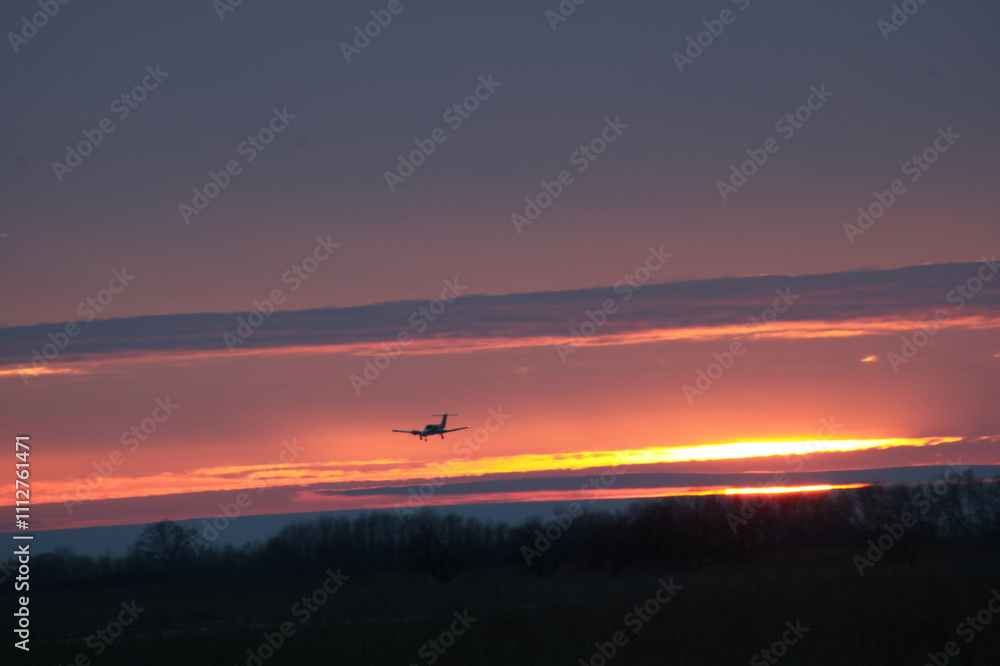 The plane lands at sunset. The photo shows the plane, clouds and a beautiful sunset The plane lands at sunset. The photo shows the plane, clouds and a beautiful sunset