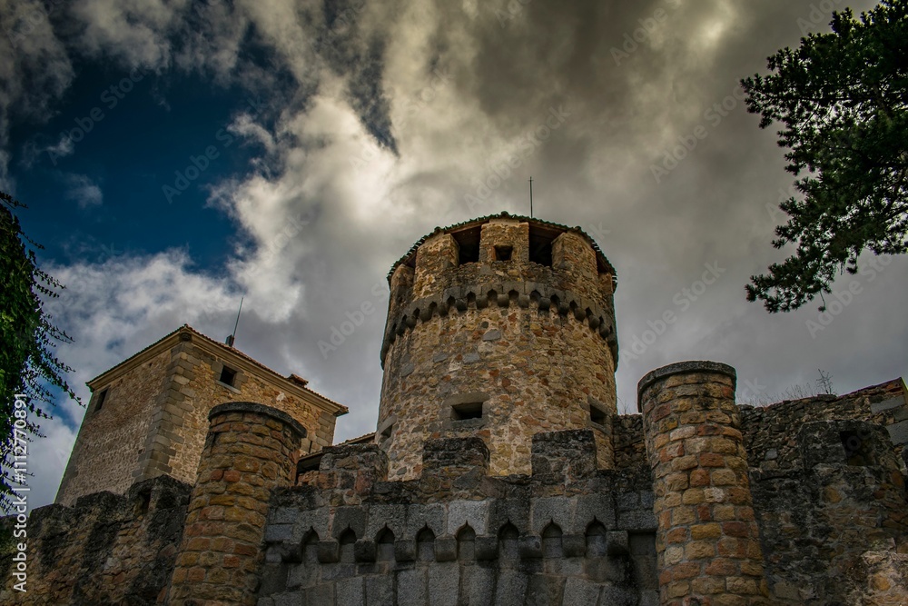 Dramatic view of an ancient stone castle tower against a cloudy sky, surrounded by lush greenery Dramatic view of an ancient stone castle tower against a cloudy sky, surrounded by lush greenery