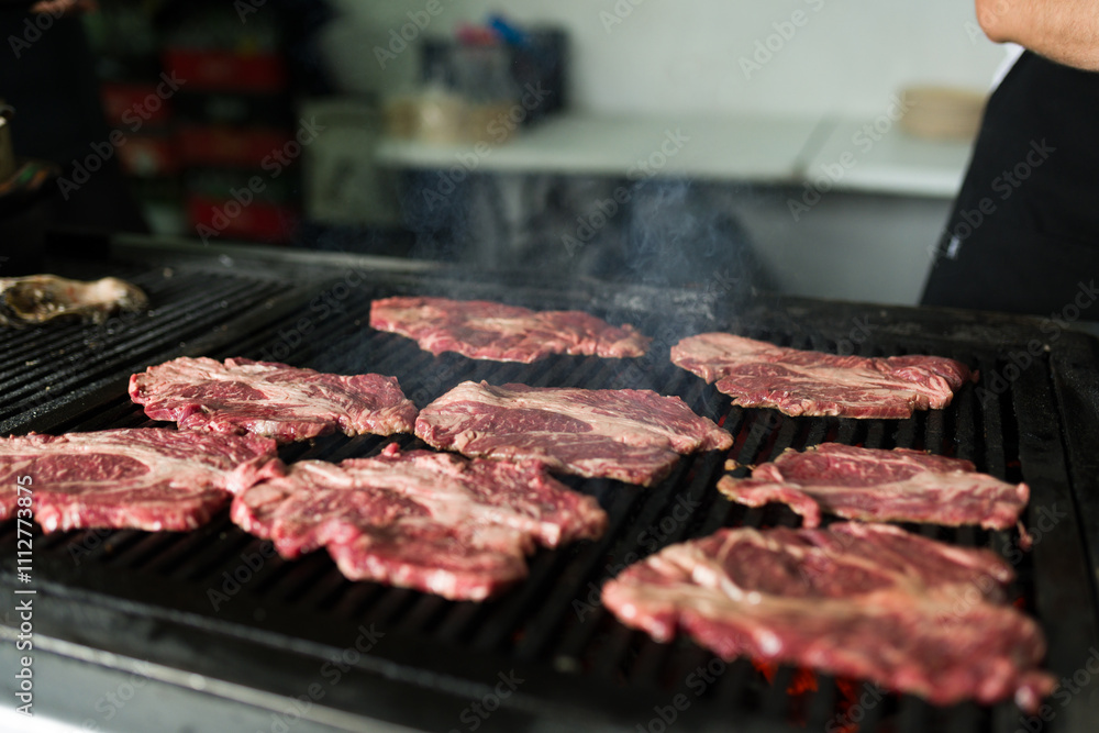 Beef steaks sizzling on a hot grill in a commercial kitchen, capturing the delicious aroma as they cook Beef steaks sizzling on a hot grill in a commercial kitchen, capturing the delicious aroma as they cook