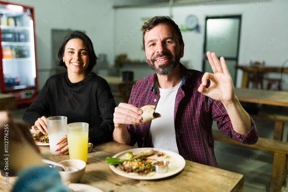 Happy man enjoying tasty tacos at an authentic mexican taqueria, giving a thumbs up and raving about the delicious food Happy man enjoying tasty tacos at an authentic mexican taqueria, giving a thumbs up and raving about the delicious food
