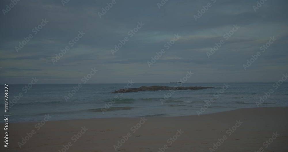 roca en medio del mar con olas con un barco de fondo en un atardecer roca en medio del mar con olas con un barco de fondo en un atardecer