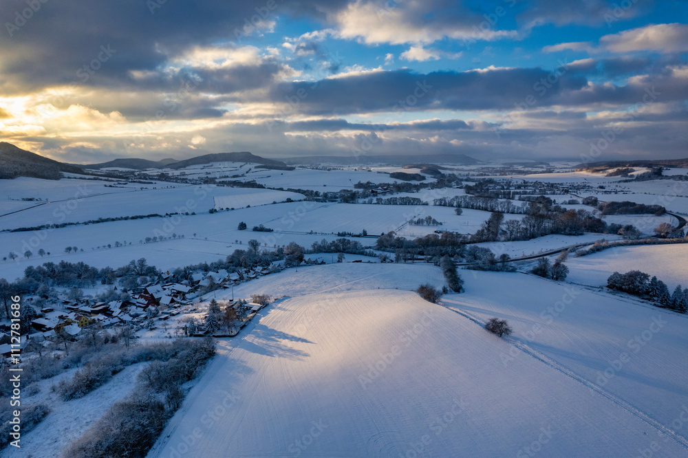 Aerial view of a small German mountain village covered by heavy snow at sunset. Germany.
