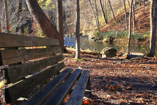 Empty Park Bench Invites Hikers To Rest By Creek photo