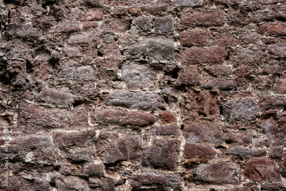 A wall made of stone with a rough texture. The wall is brown and white