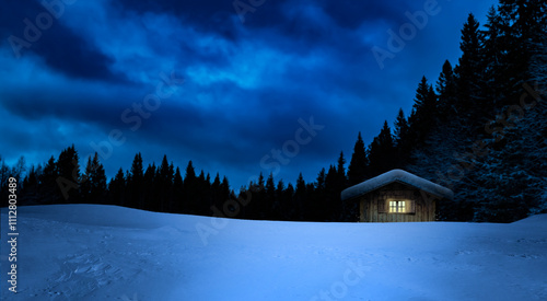 Gemütliches Cottages mit beleuchtetem Fenster in verschneitem Winterwald