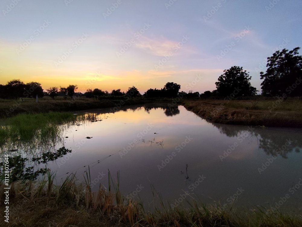 A serene river view with the sun rising or setting over calm waters and vibrant skies A serene river view with the sun rising or setting over calm waters and vibrant skies