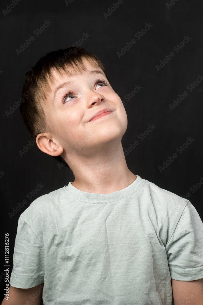 Studio portrait of a 7-year-old child wearing a light blue t-shirt against a black chalkboard background. Perfect for educational, childhood, or school-themed stock photography. Studio portrait of a 7-year-old child wearing a light blue t-shirt against a black chalkboard background. Perfect for educational, childhood, or school-themed stock photography.