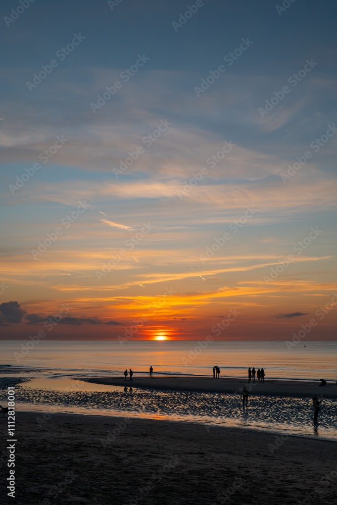 silhouettes of people against the background of the sea and an orange and cloudy sunset silhouettes of people against the background of the sea and an orange and cloudy sunset