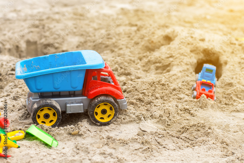 Colorful toy dump truck and other toys in a sandbox, perfect for children's playtime and outdoor activities. Ideal for stock photos related to childhood, fun, and creativity. Colorful toy dump truck and other toys in a sandbox, perfect for children's playtime and outdoor activities. Ideal for stock photos related to childhood, fun, and creativity.