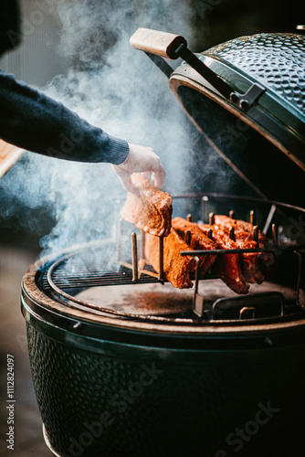 smoky barbecue grilling ribs in open bbq with wooden handles. photo