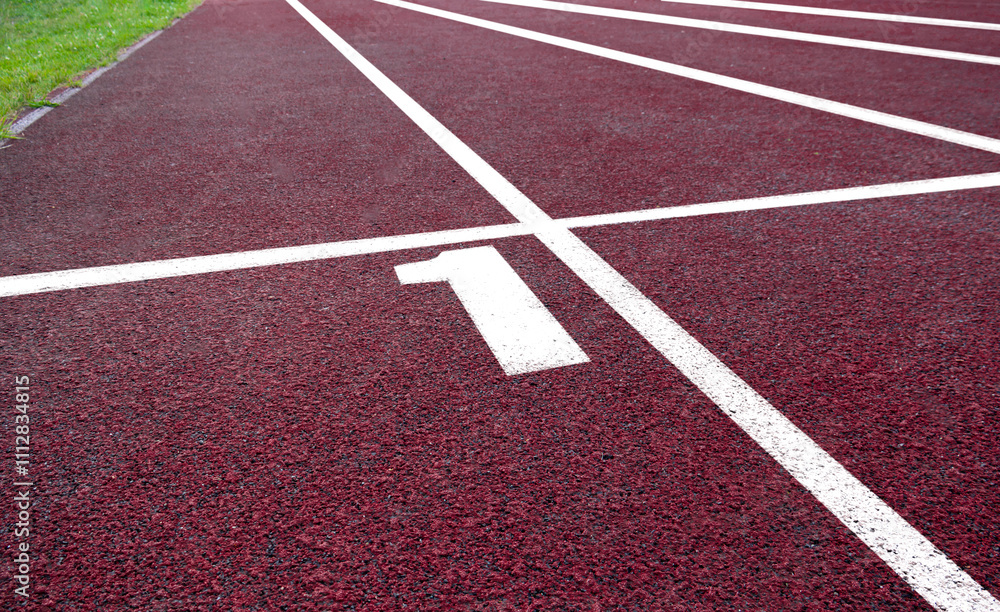 Red running track lane number one with clear white markings under bright sunlight Red running track lane number one with clear white markings under bright sunlight