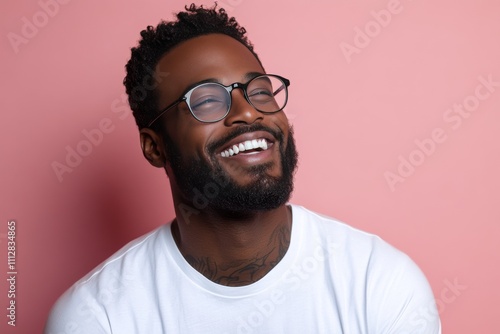 Smiling man with glasses in a casual outfit against a pink background
