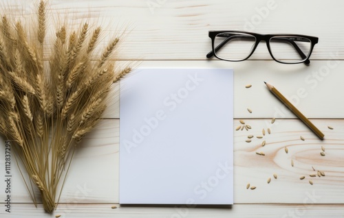 Blank notebook beside glasses and wheat stalks on wooden surface creating a c...