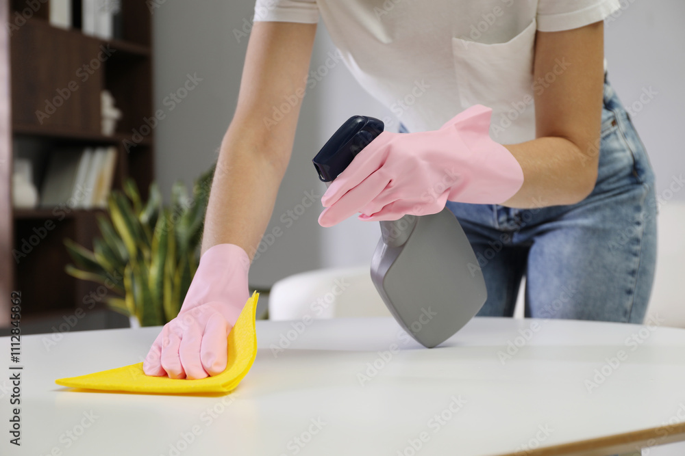 Young woman cleaning table with rag and spray in office, closeup Young woman cleaning table with rag and spray in office, closeup