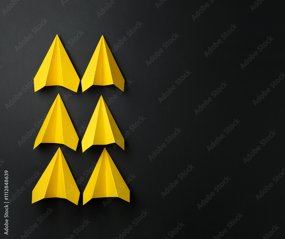 Handmade yellow paper planes on black background, top view. Space for text Handmade yellow paper planes on black background, top view. Space for text