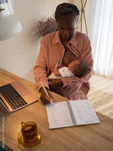 Woman planning budget and breastfeeding her child photo