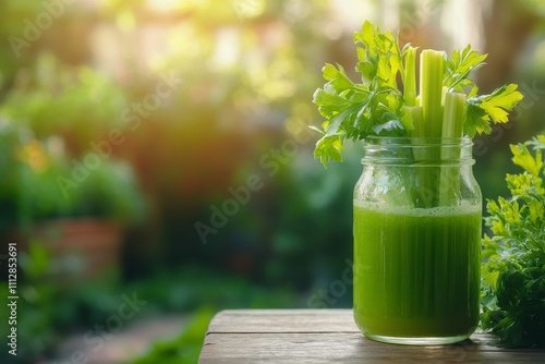 Refreshing green drink in a jar with celery on a wooden table during daytime