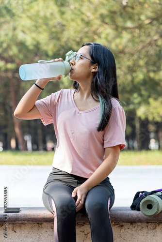 Sportswoman refreshes herself with water during a pause in her workout photo