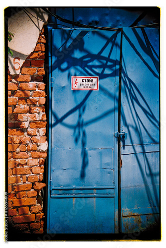 Blue door with shadows and warning sign on a brick wall. photo