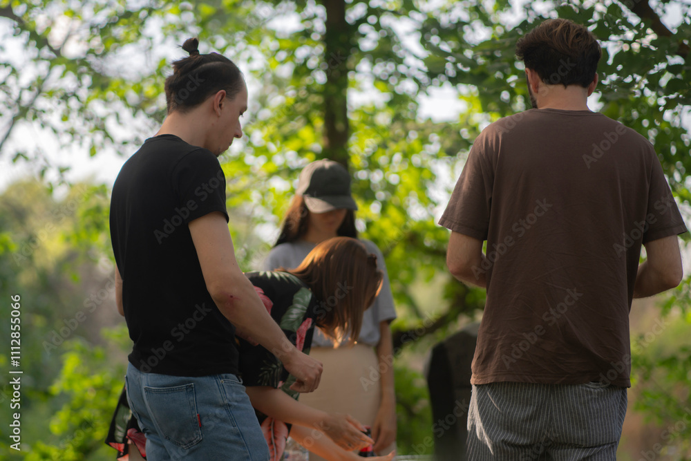 people prepare food for a picnic in a wooded area. standing near a table with food and drinks people prepare food for a picnic in a wooded area. standing near a table with food and drinks