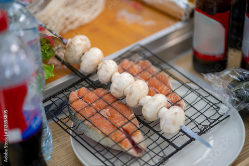 womans hand holds a skewer with mushrooms at an outdoor picnic, prepare to cook them on fire photo