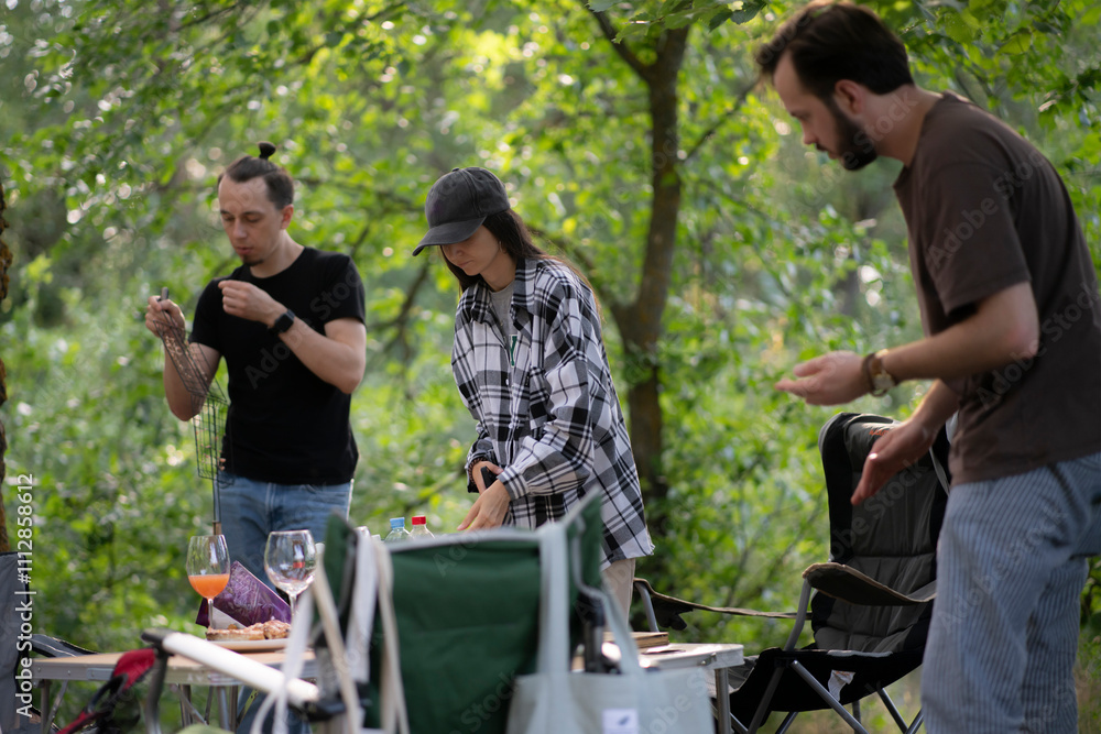 Four friends gather around a table in a lush, green forest on a sunny afternoon for a relaxing picnic Four friends gather around a table in a lush, green forest on a sunny afternoon for a relaxing picnic