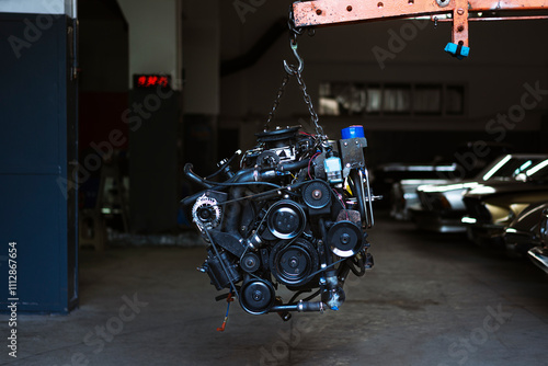 Automobile motor hanging on a crane in a garage
