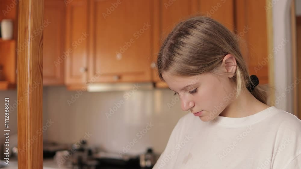 Young woman stands in a kitchen, putting on a baseball cap while admiring her reflection in the mirror. A moment of self-expression and confidence during her morning routine Young woman stands in a kitchen, putting on a baseball cap while admiring her reflection in the mirror. A moment of self-expression and confidence during her morning routine
