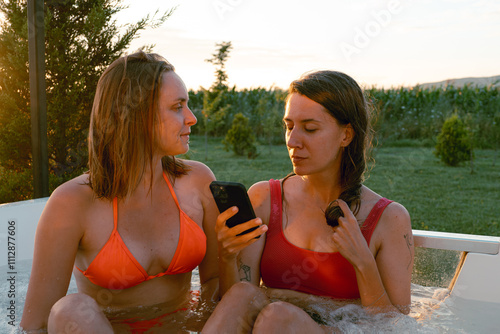 Two women enjoying a sunset soak in a hot tub at dusk