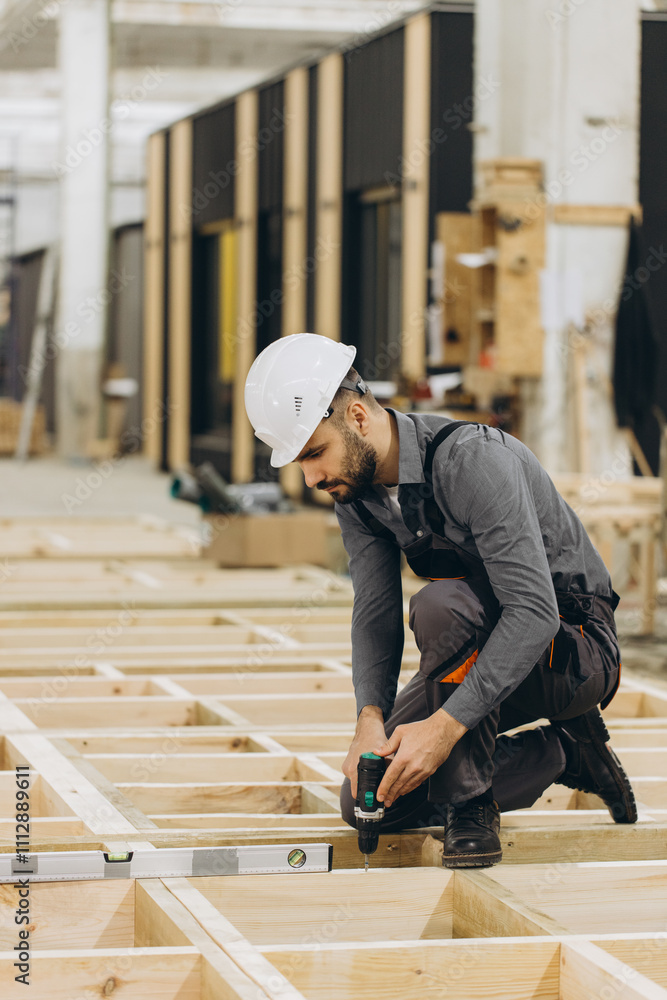 Construction worker building wooden frame using spirit level and drill in modular building industry Construction worker building wooden frame using spirit level and drill in modular building industry