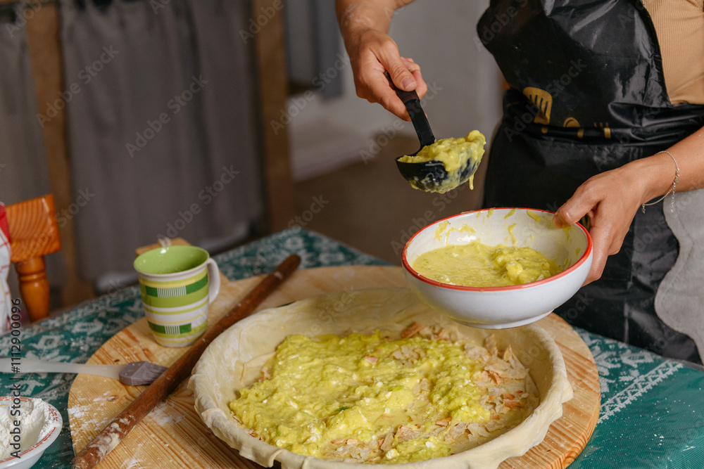 woman putting a fillig with zucchini and cheese to bake a byrek