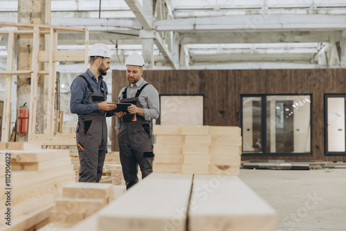 Construction workers using digital tablet in modular building factory