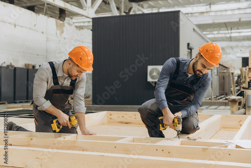 Carpenters building wooden frame for modular house in factory