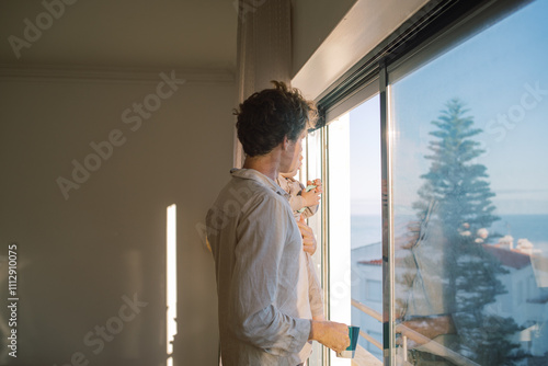 Father and baby looking out the window at ocean view photo