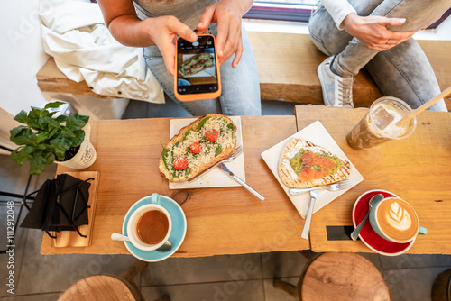 Woman taking pictures of food in cafe with smartphone photo