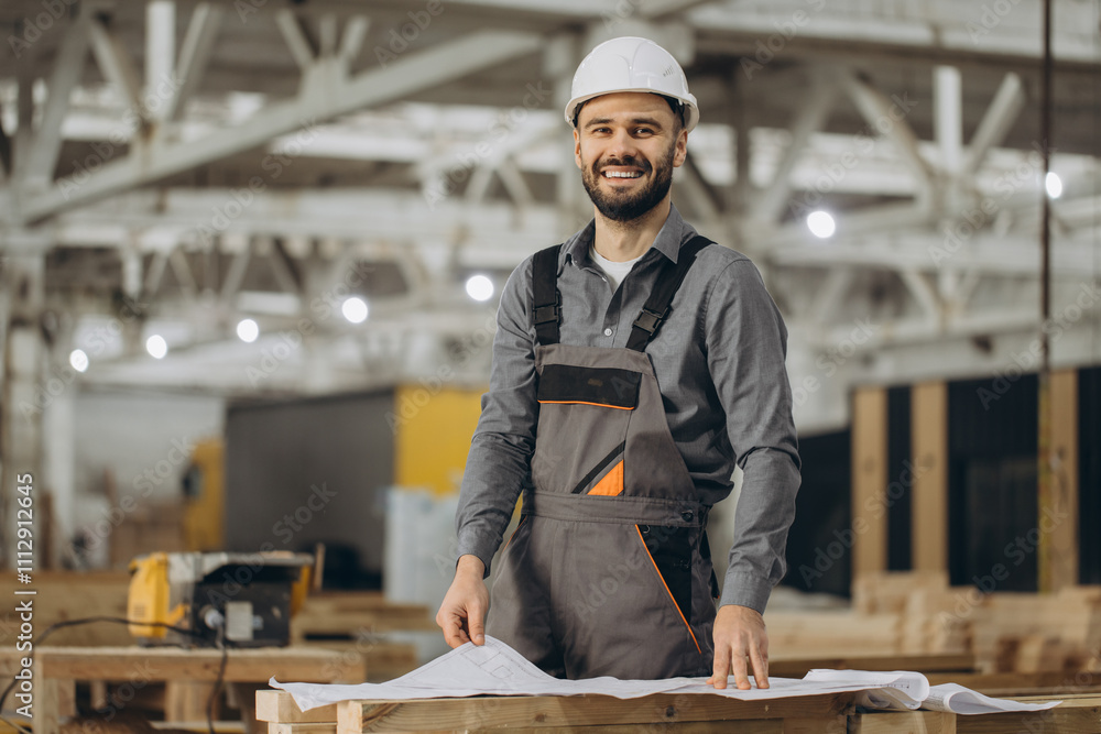 Smiling engineer reading blueprints in modular building factory Smiling engineer reading blueprints in modular building factory