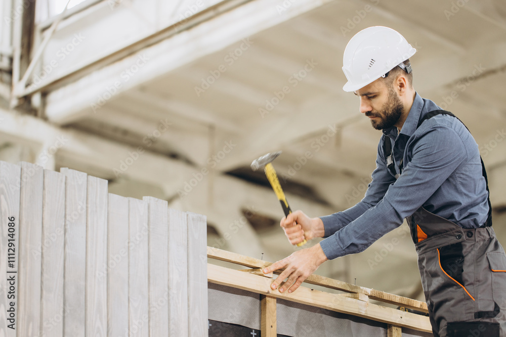 Construction worker building modular house with hammer and nails Construction worker building modular house with hammer and nails