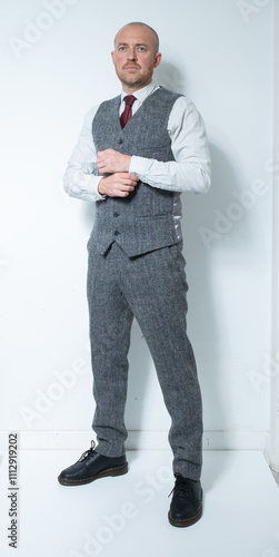 A modern corporate man in a tailored tweed three piece suit. Grey tweed knit business suit for lawyers, bankers and for men with high power positions. Corporate barrister and peaky blinders cos play. photo