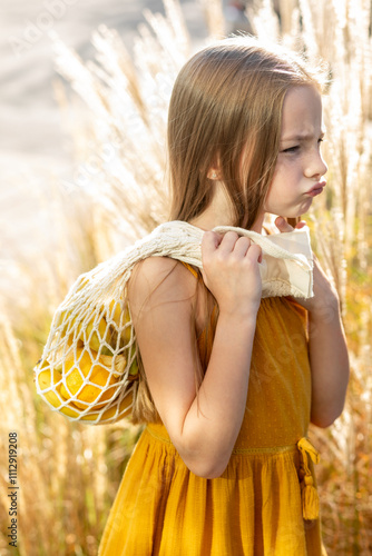 Little girl holding shopping bag with fruits photo