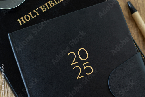 2025 calendar notebook with holy bible book. Close-up. Top view. Christian education, learning, devotion, studying scripture, biblical concept. photo