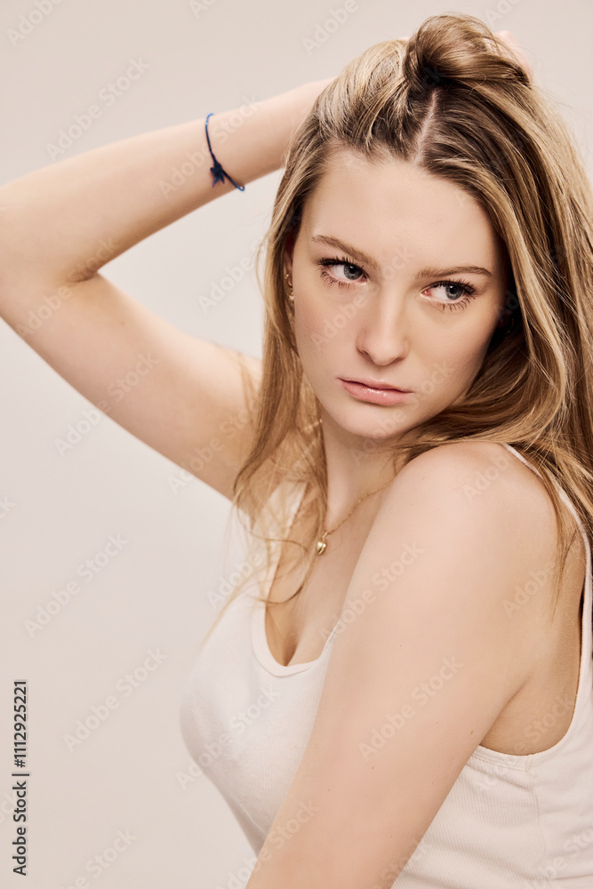 Portrait of young beautiful woman sitting on a stool in a studio setting. Portrait of young beautiful woman sitting on a stool in a studio setting.